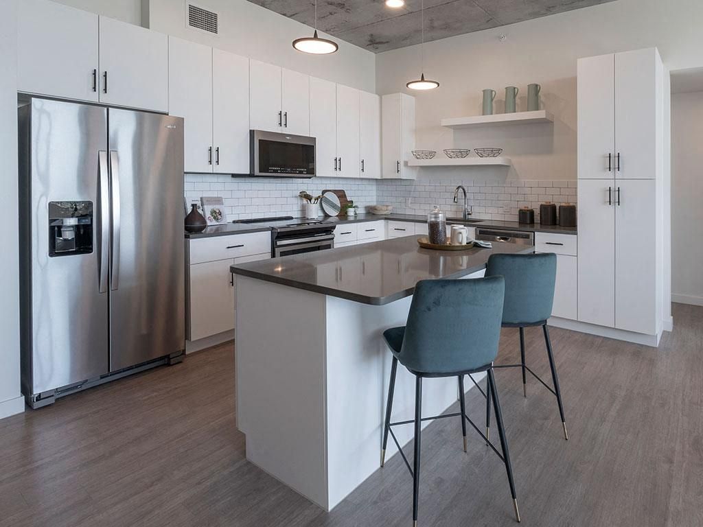 Modern kitchen with stainless steel appliances, white cabinetry, and a central island with stools.