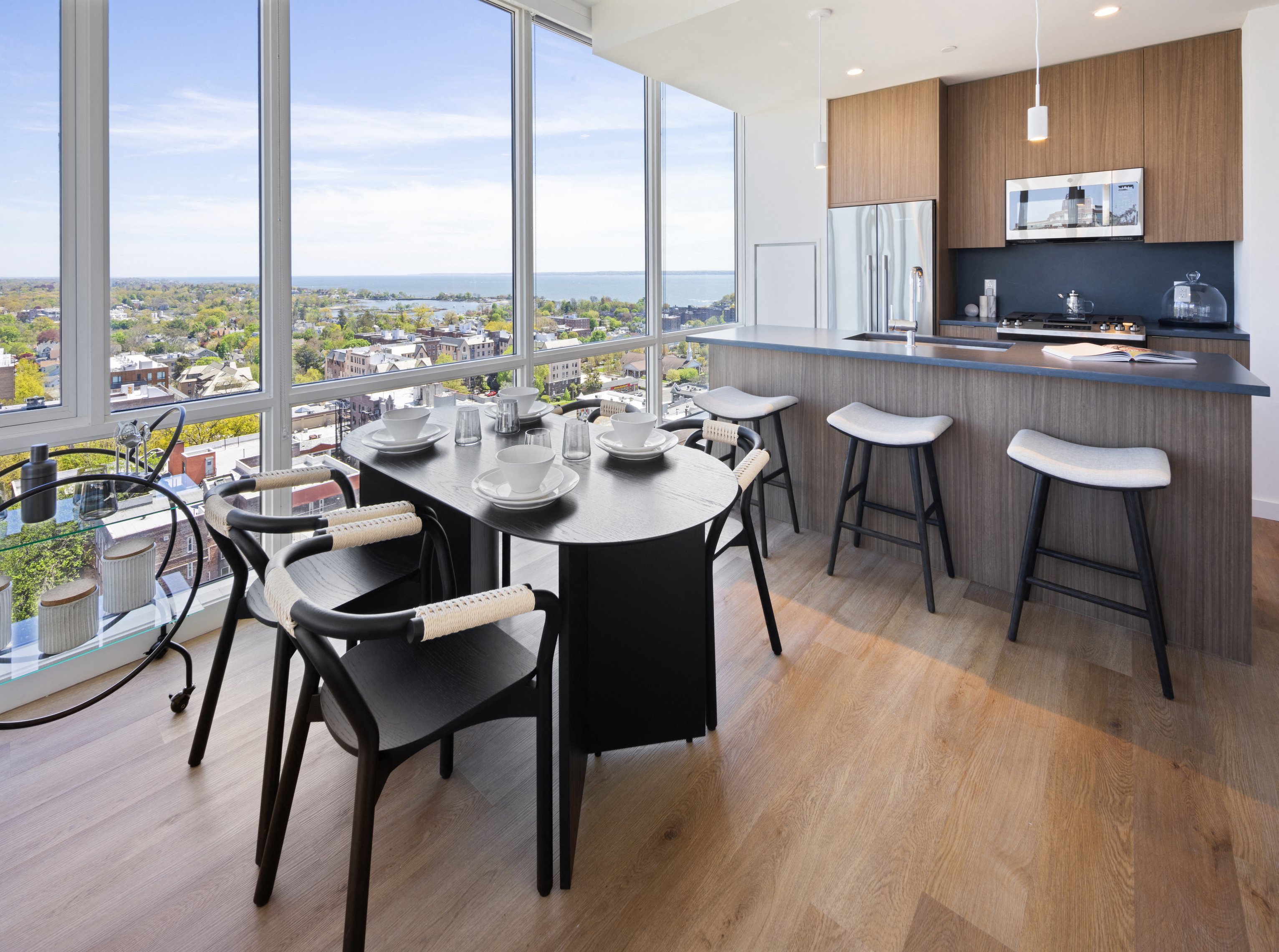 Modern dining area with a view, featuring a table, chairs, and a kitchen bar.