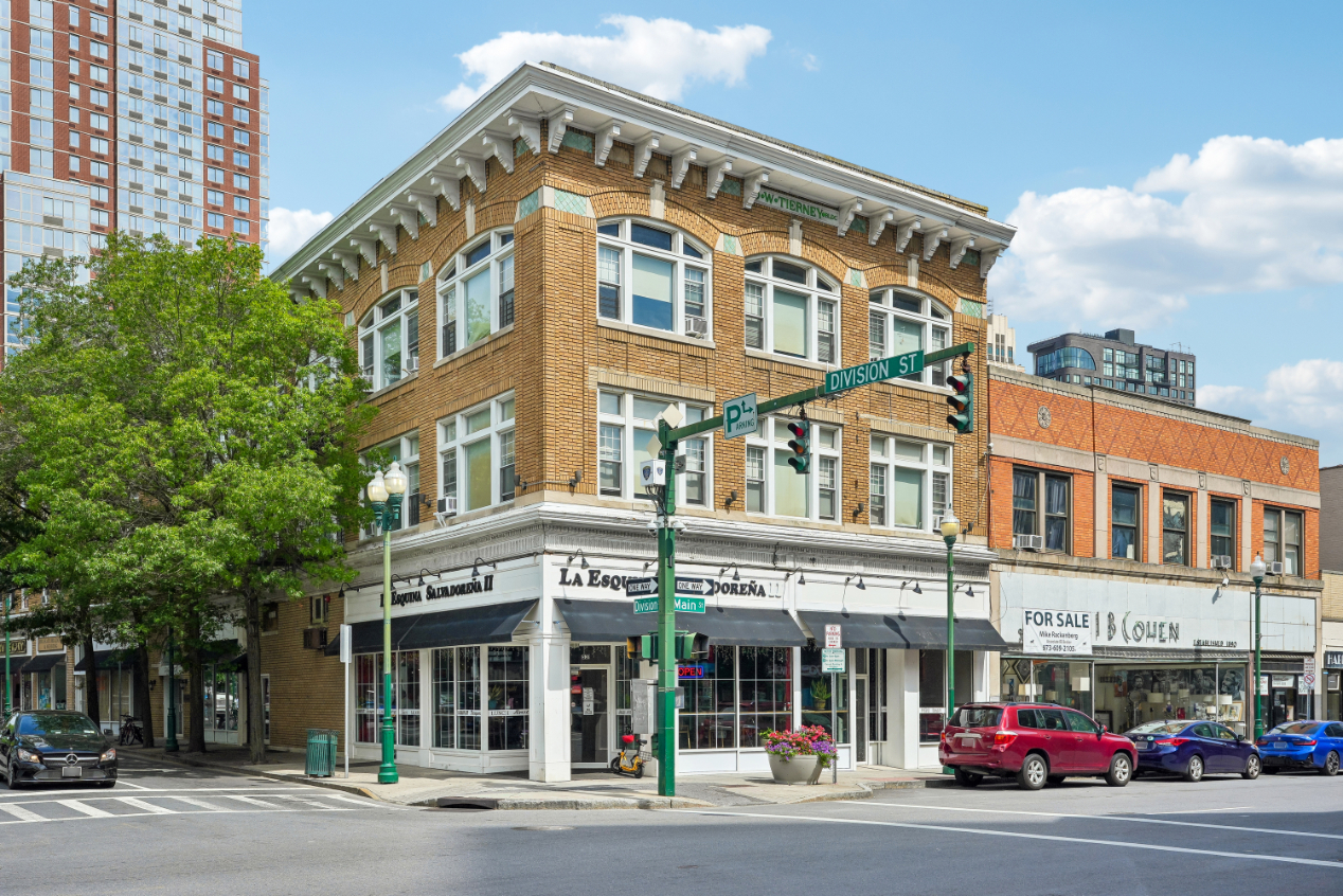 Historic brick building at an urban intersection with large windows.