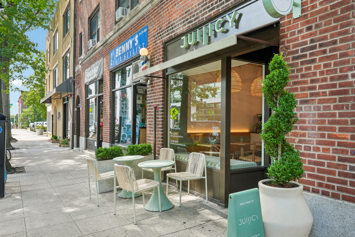 Outdoor seating area of a modern cafe with brick building and greenery.