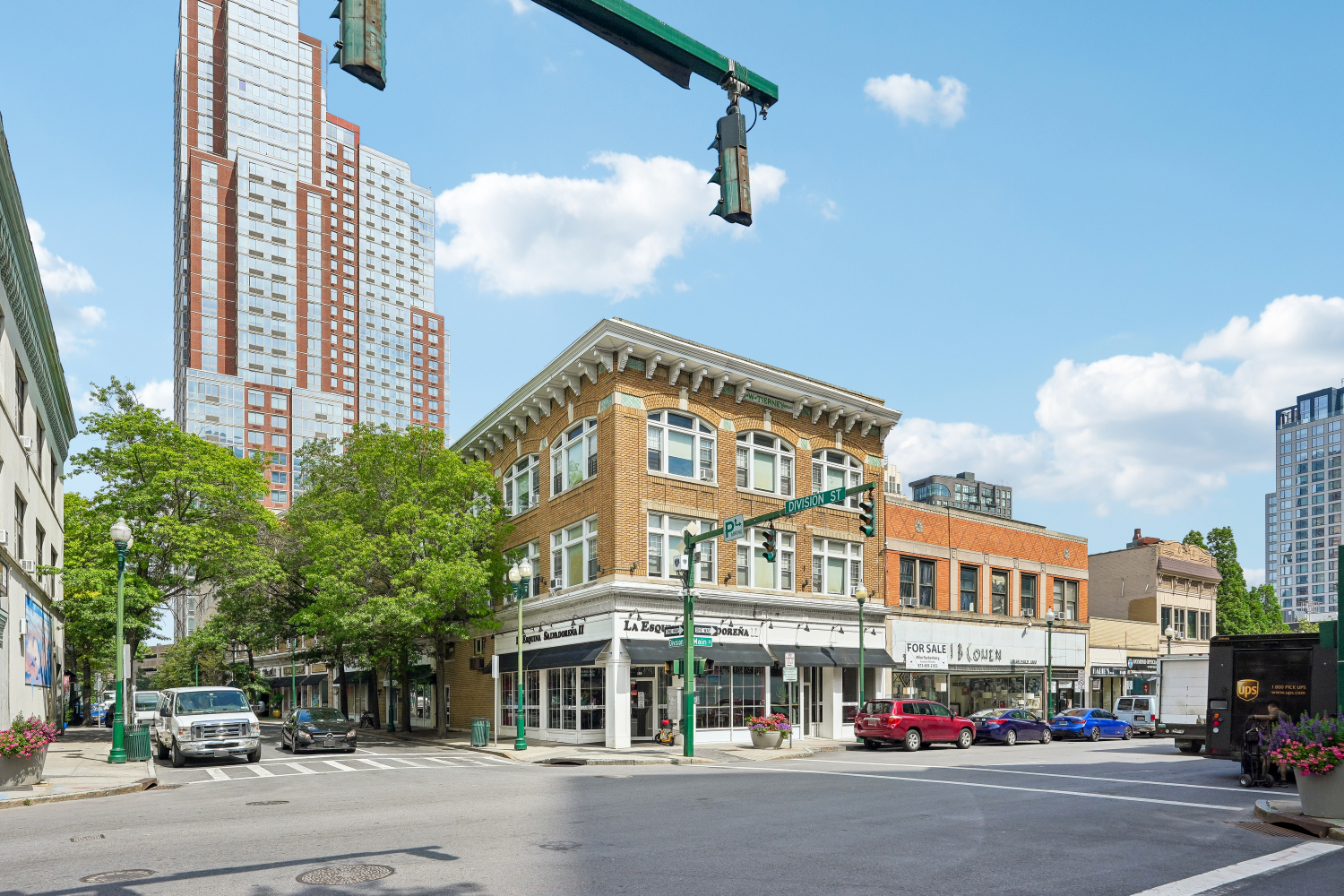 Street corner with modern buildings and a historic brick structure.