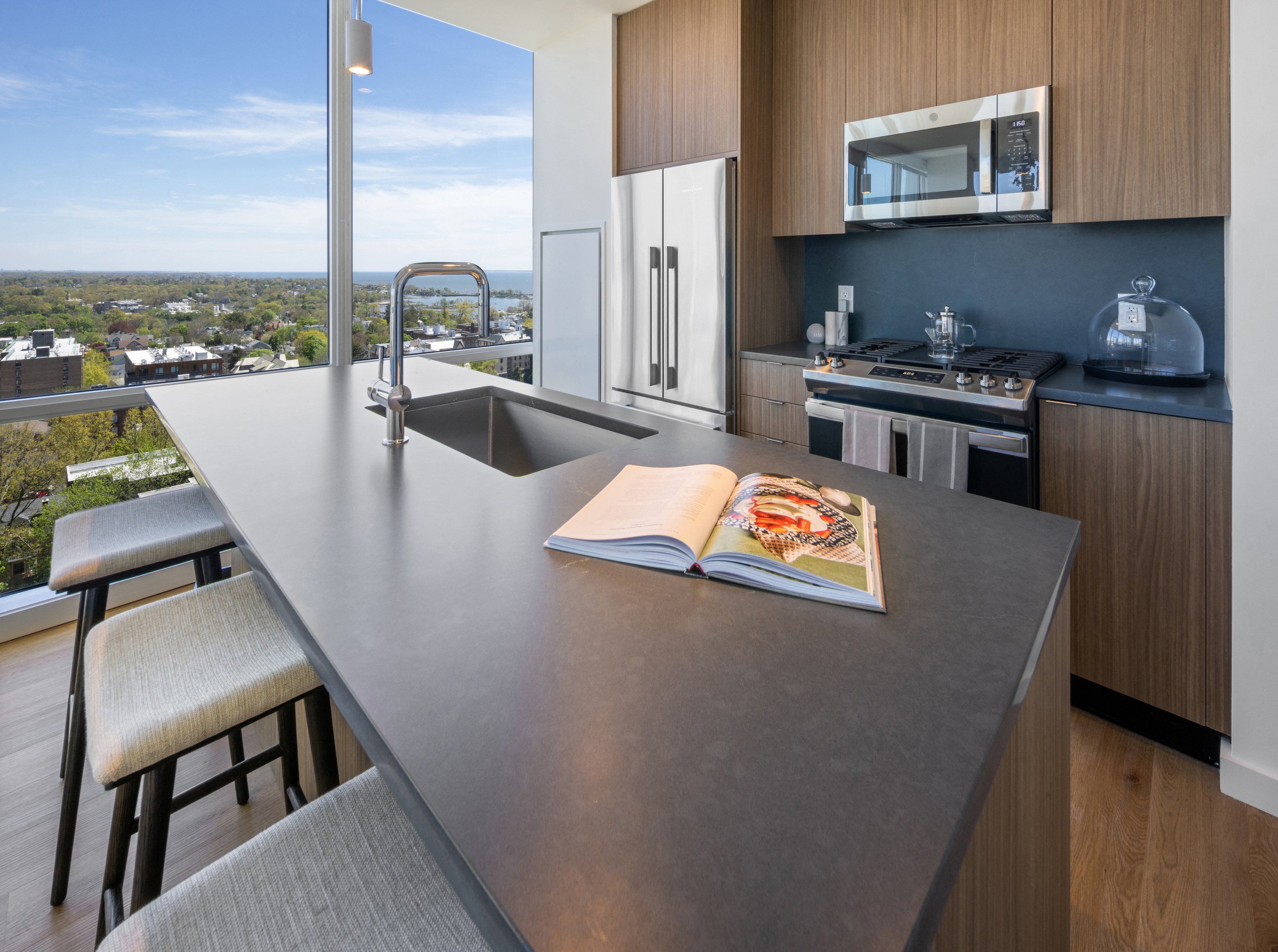 Modern kitchen with a sleek island, open layout, and a scenic view.