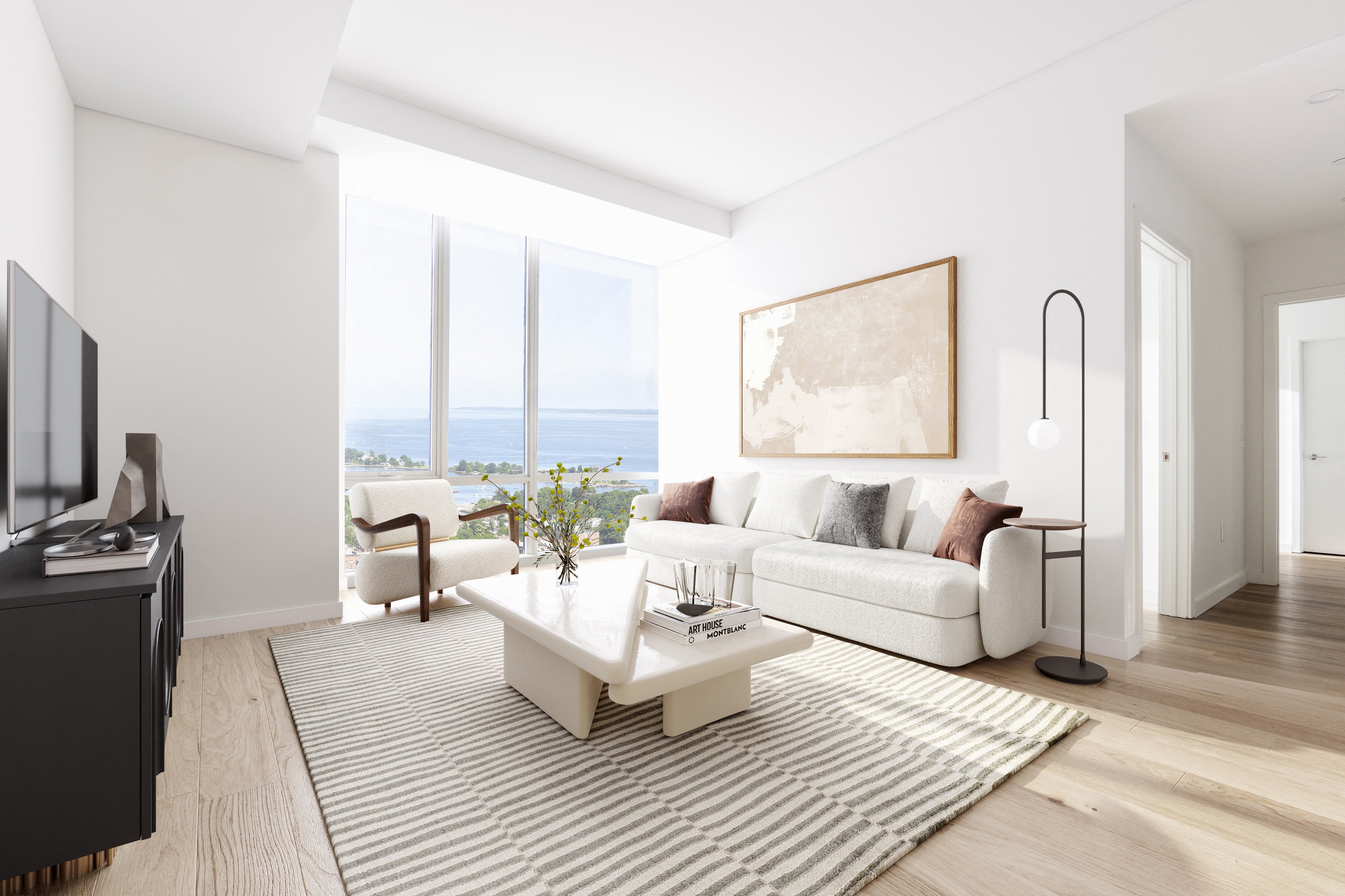 Bright living room with a white sofa, coffee table, and large windows overlooking the ocean.