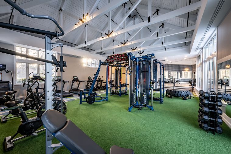 Modern gym interior with various exercise equipment and green turf flooring.