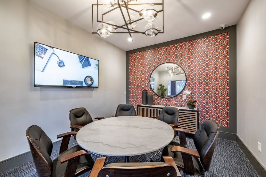 Modern conference room with a round table, six chairs, and patterned accent wall.