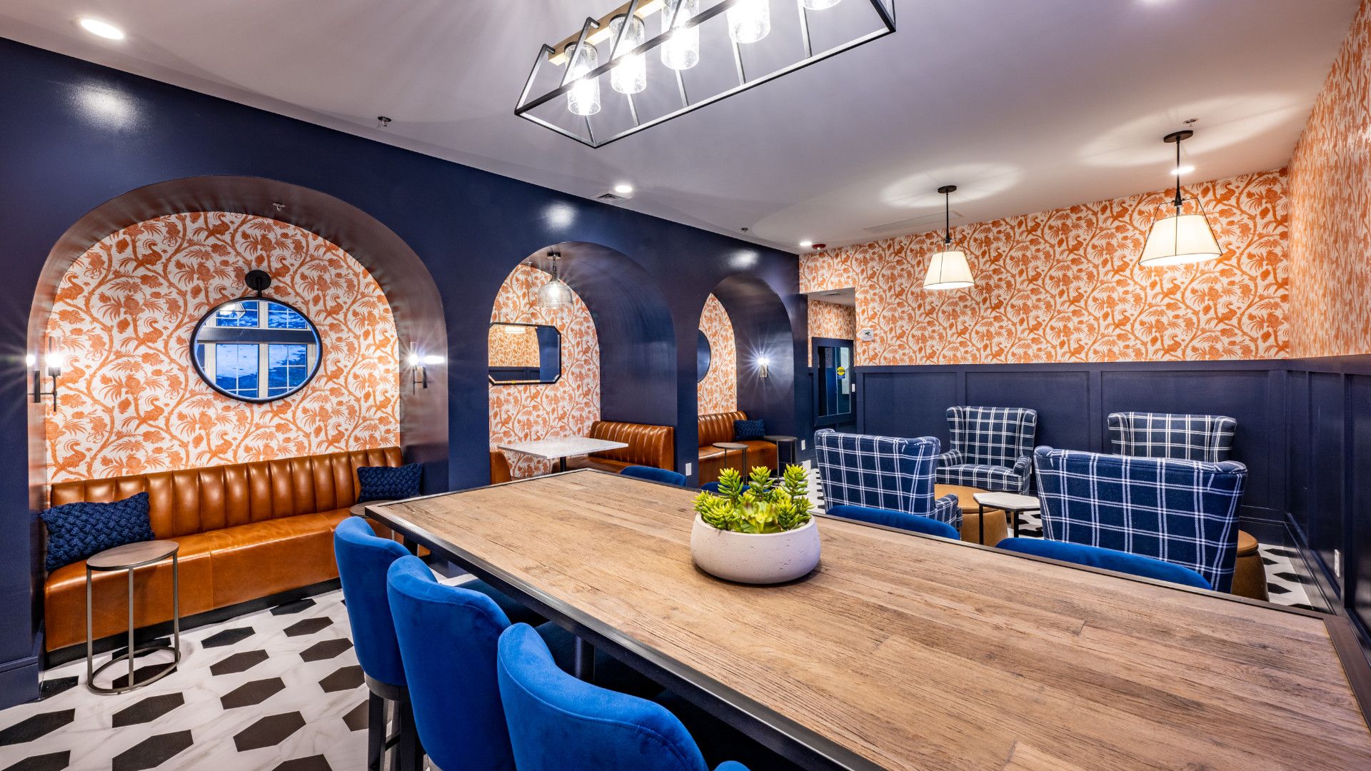 Modern lounge with patterned walls, blue furniture, and a large wooden table.