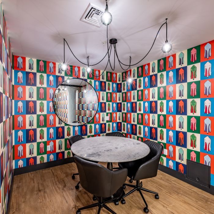 Colorful patterned wall in a small meeting room with a round table and two black chairs.