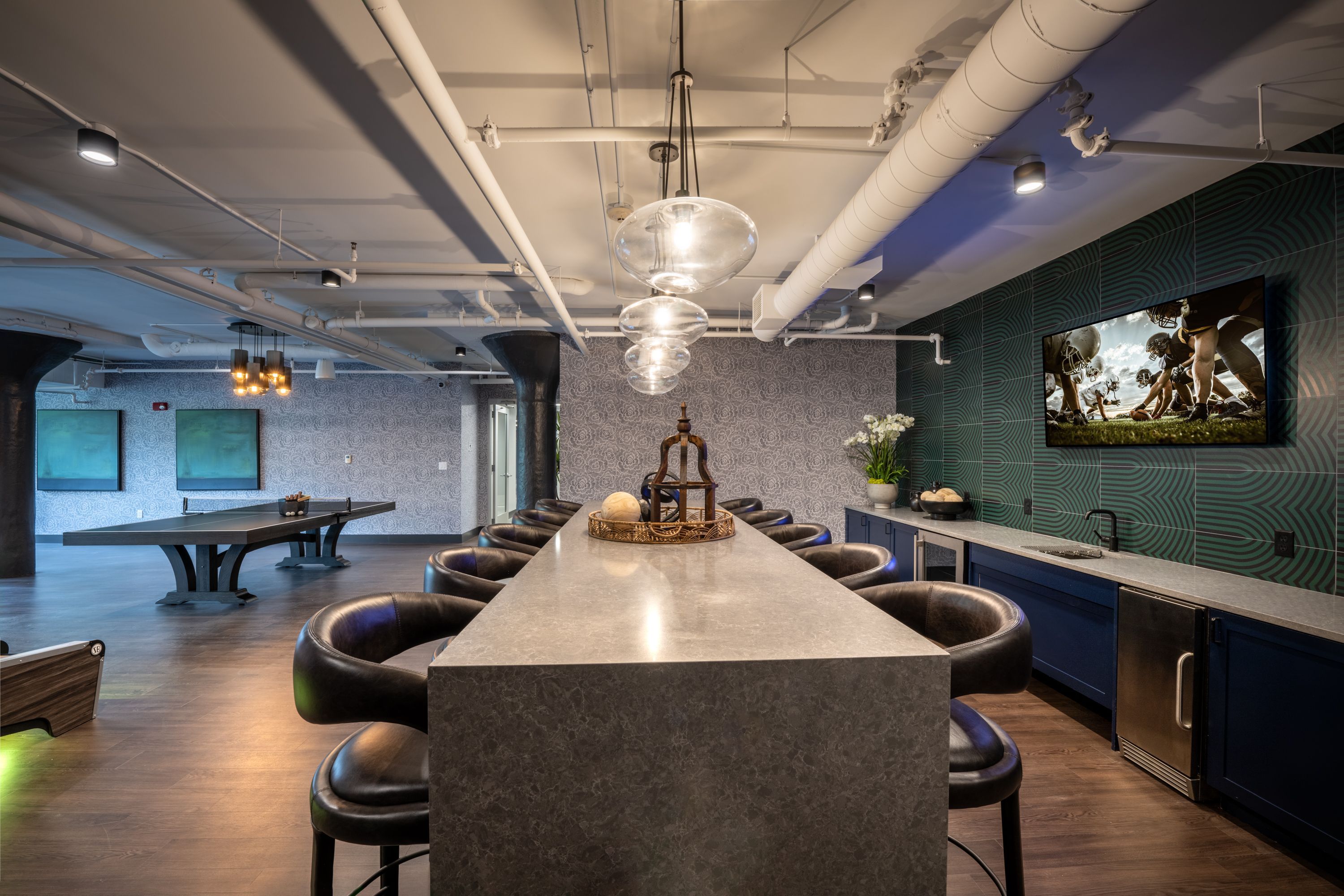 Modern interior with a long table, chairs, and a decorative TV wall in a lounge area.
