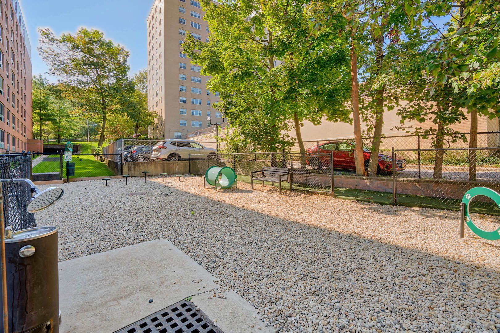 Gravel playground with trees and apartment buildings in the background.