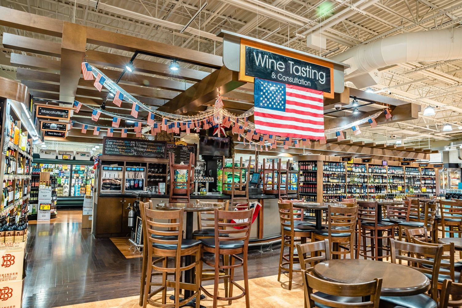 Wine tasting area in a grocery store with an American flag and seating.
