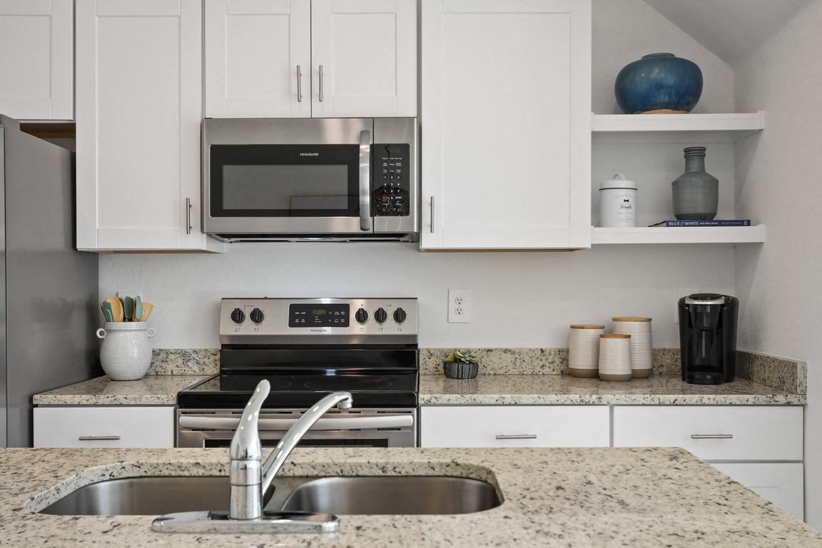 Modern kitchen with white cabinets, granite countertops, and stainless steel appliances.