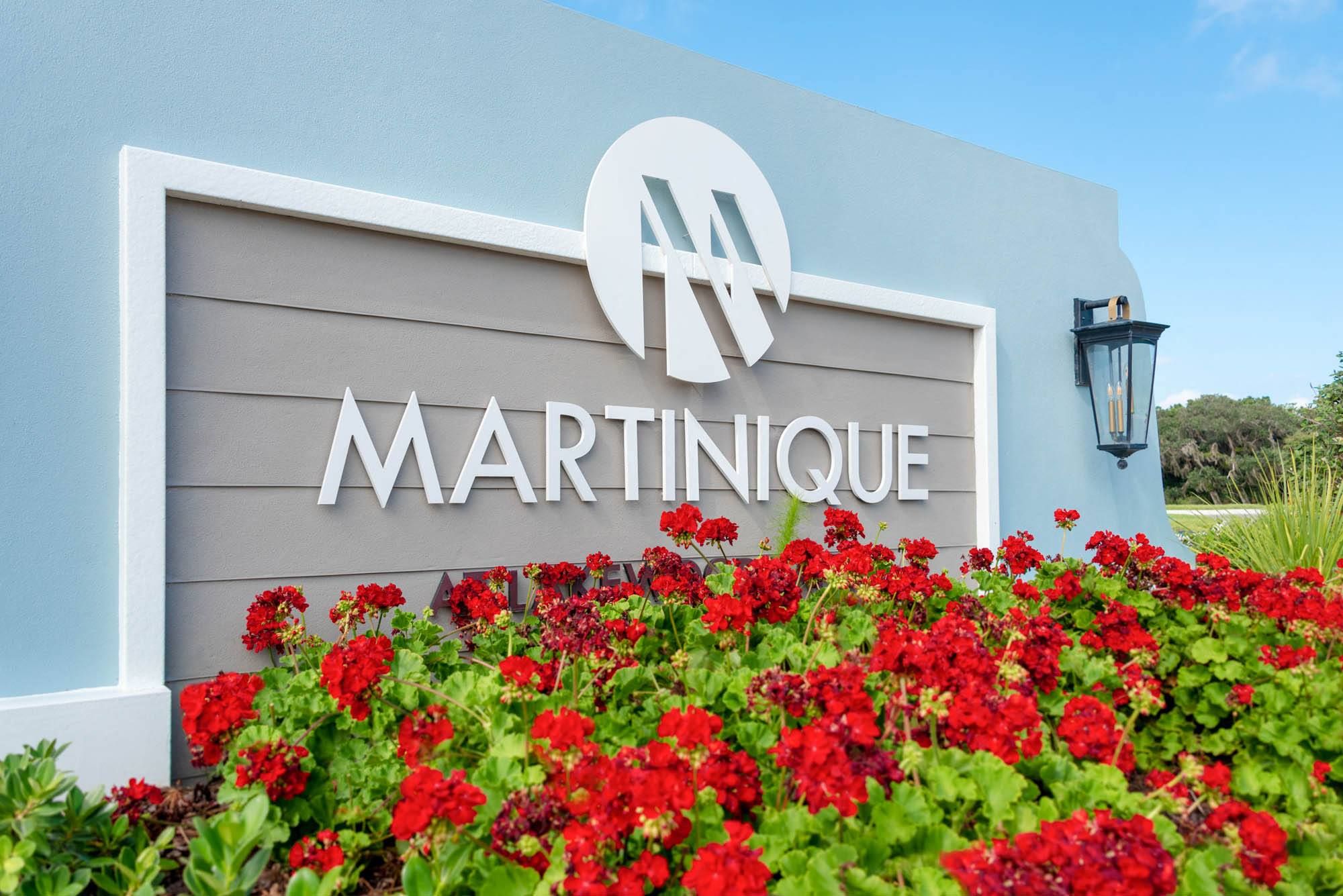 Sign for Martinique surrounded by red flowers against a light blue background.