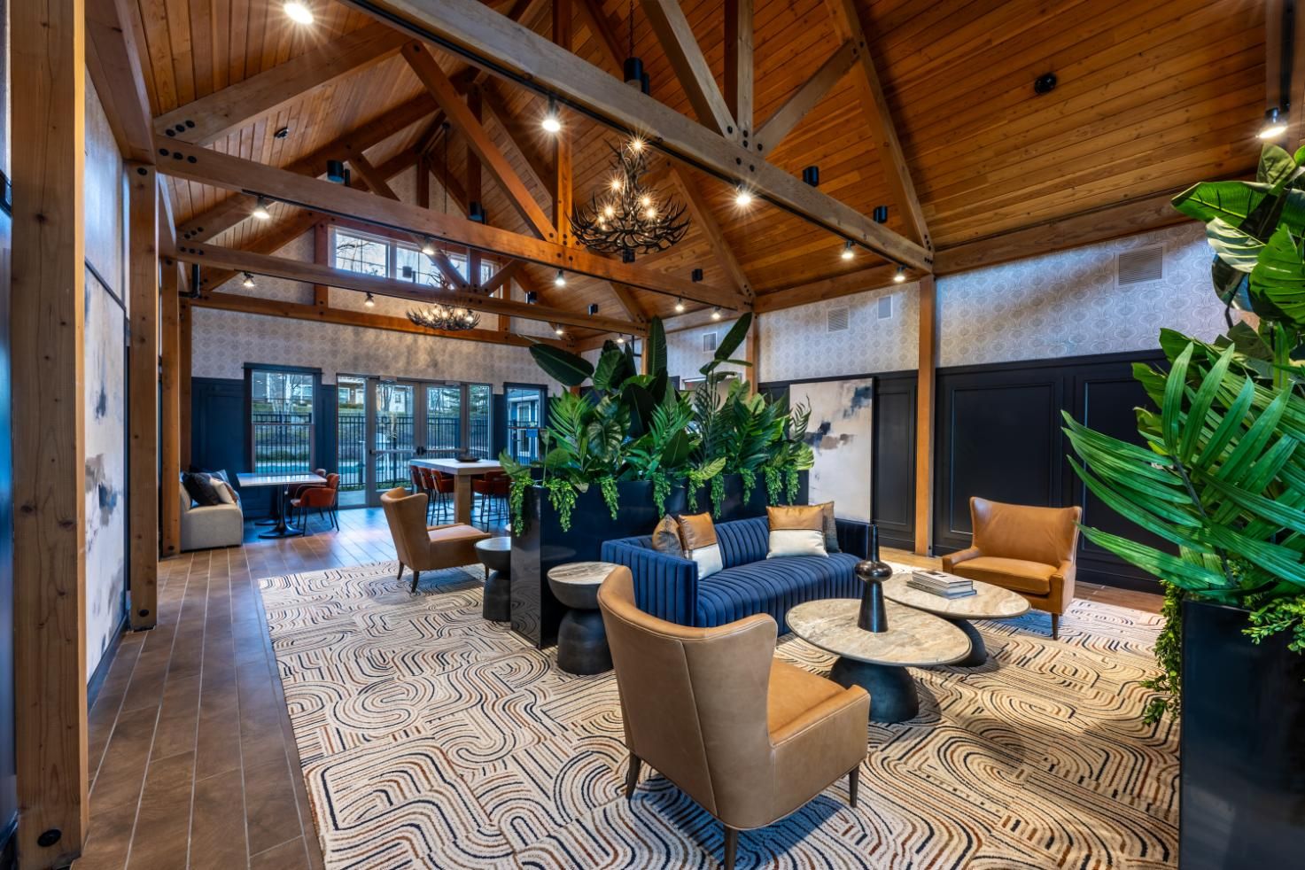 Spacious, stylish lobby with wooden beams, plants, and modern seating arrangements.