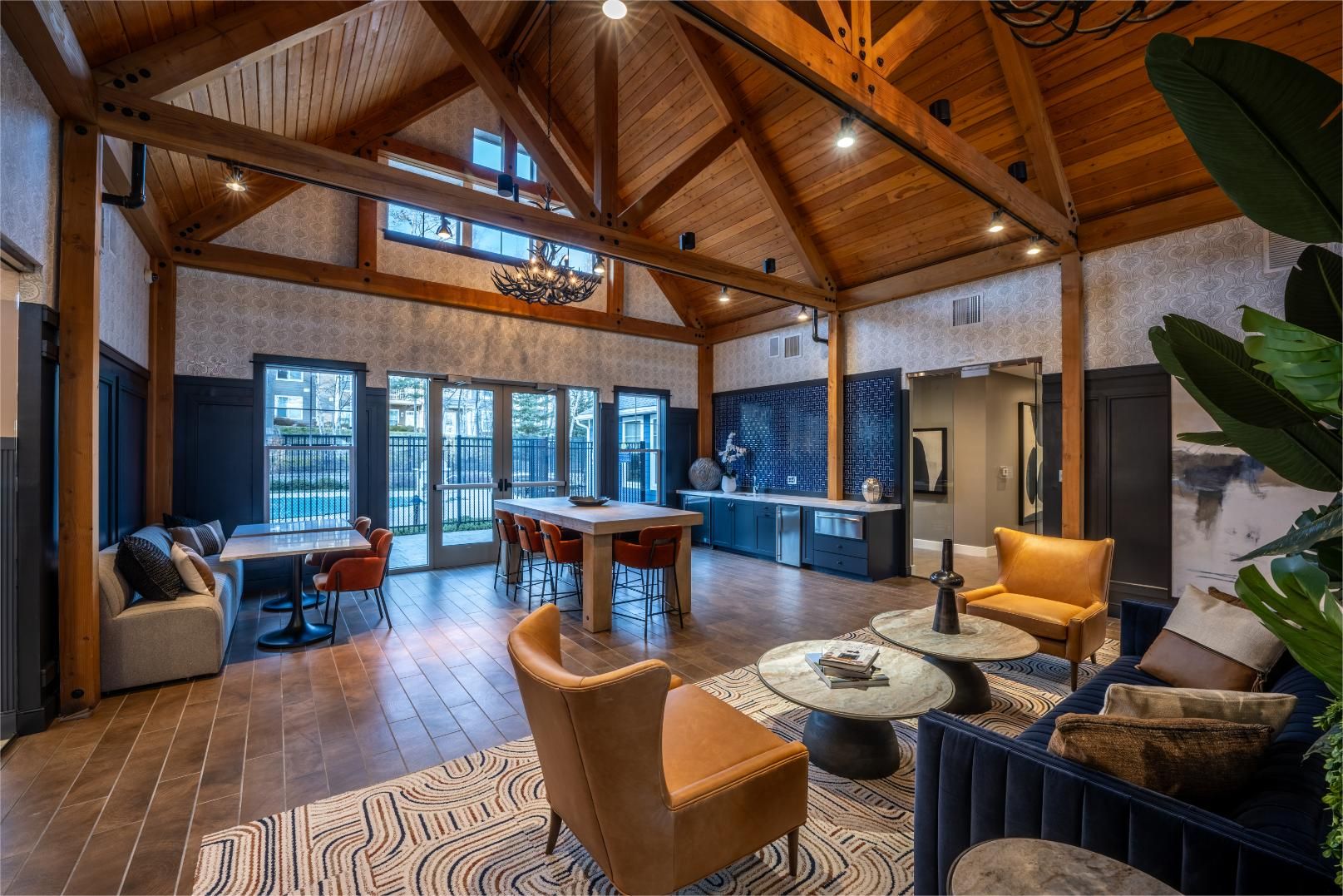 Modern lounge with wooden beams, cozy seating, and large windows.