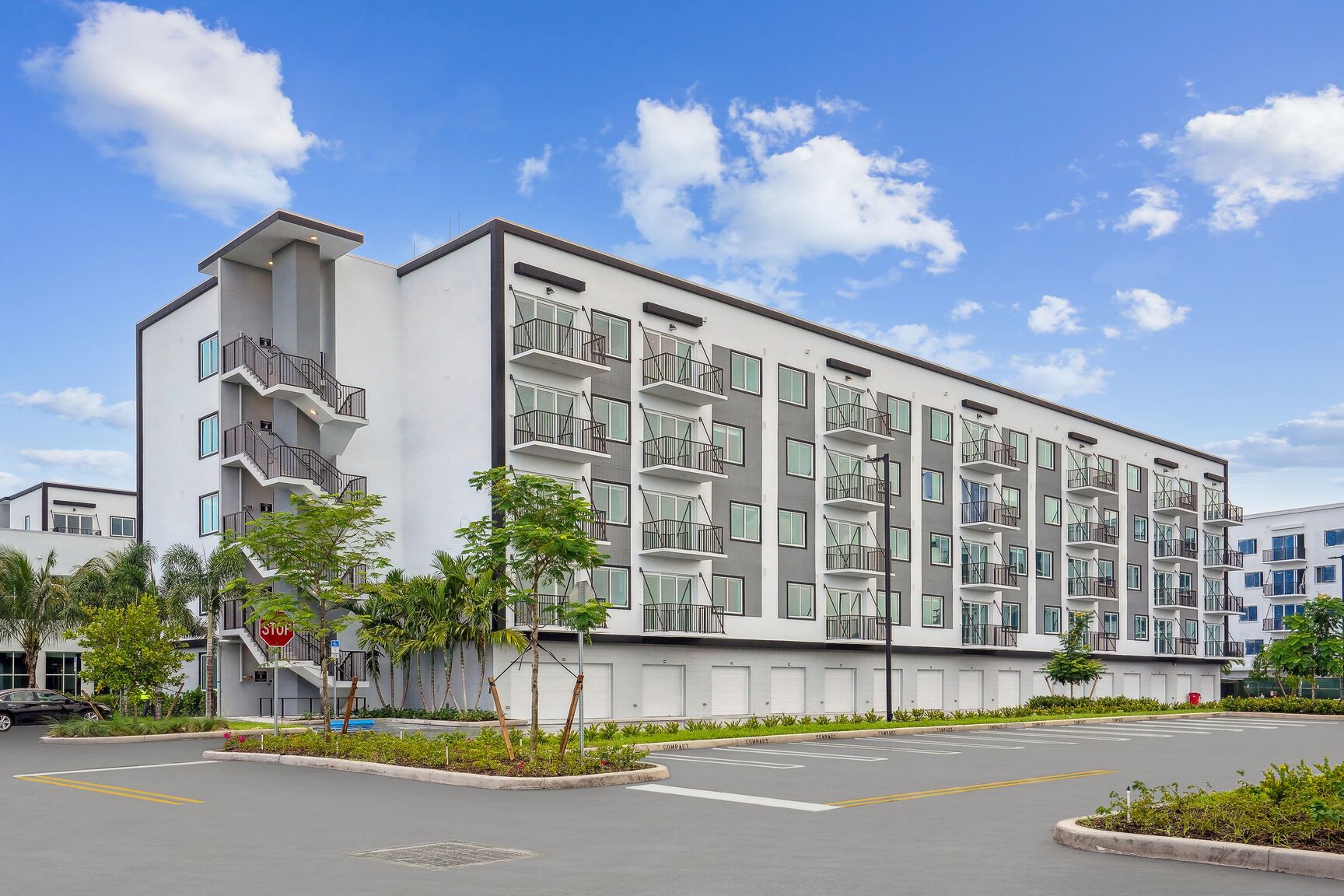 Modern multi-story building with balconies under a clear blue sky.