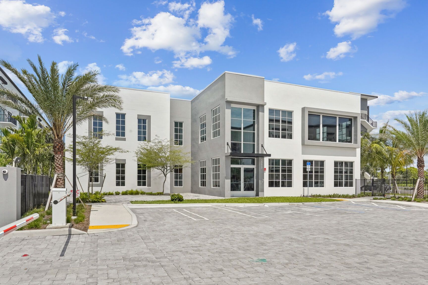 Modern two-story white building with large windows and a landscaped area.