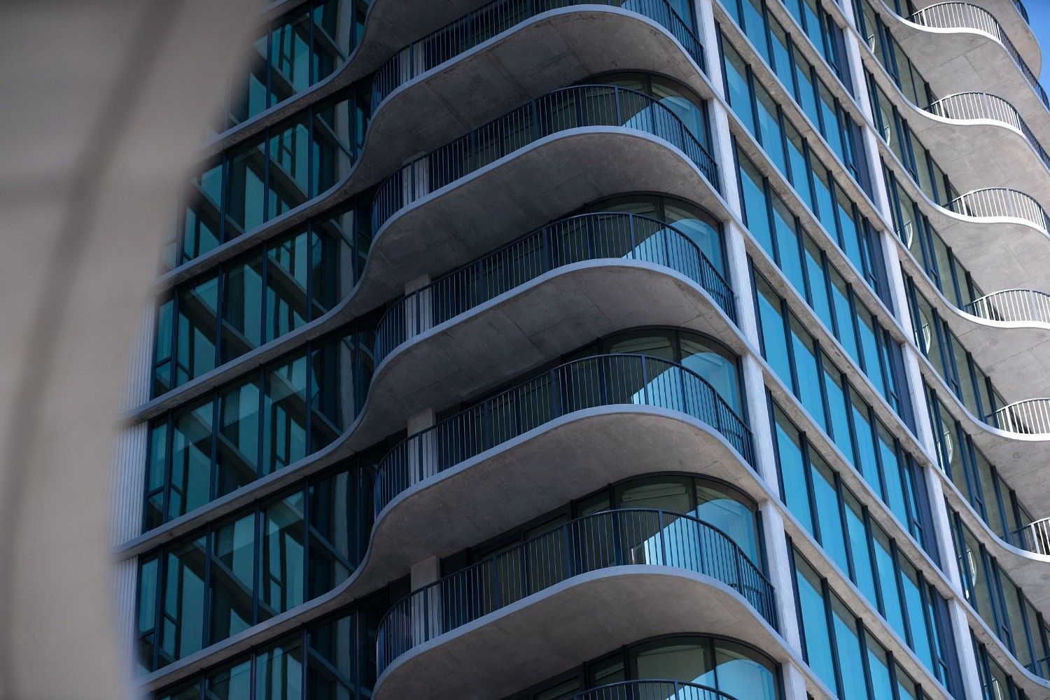 Modern building facade with curved balconies and large glass windows.
