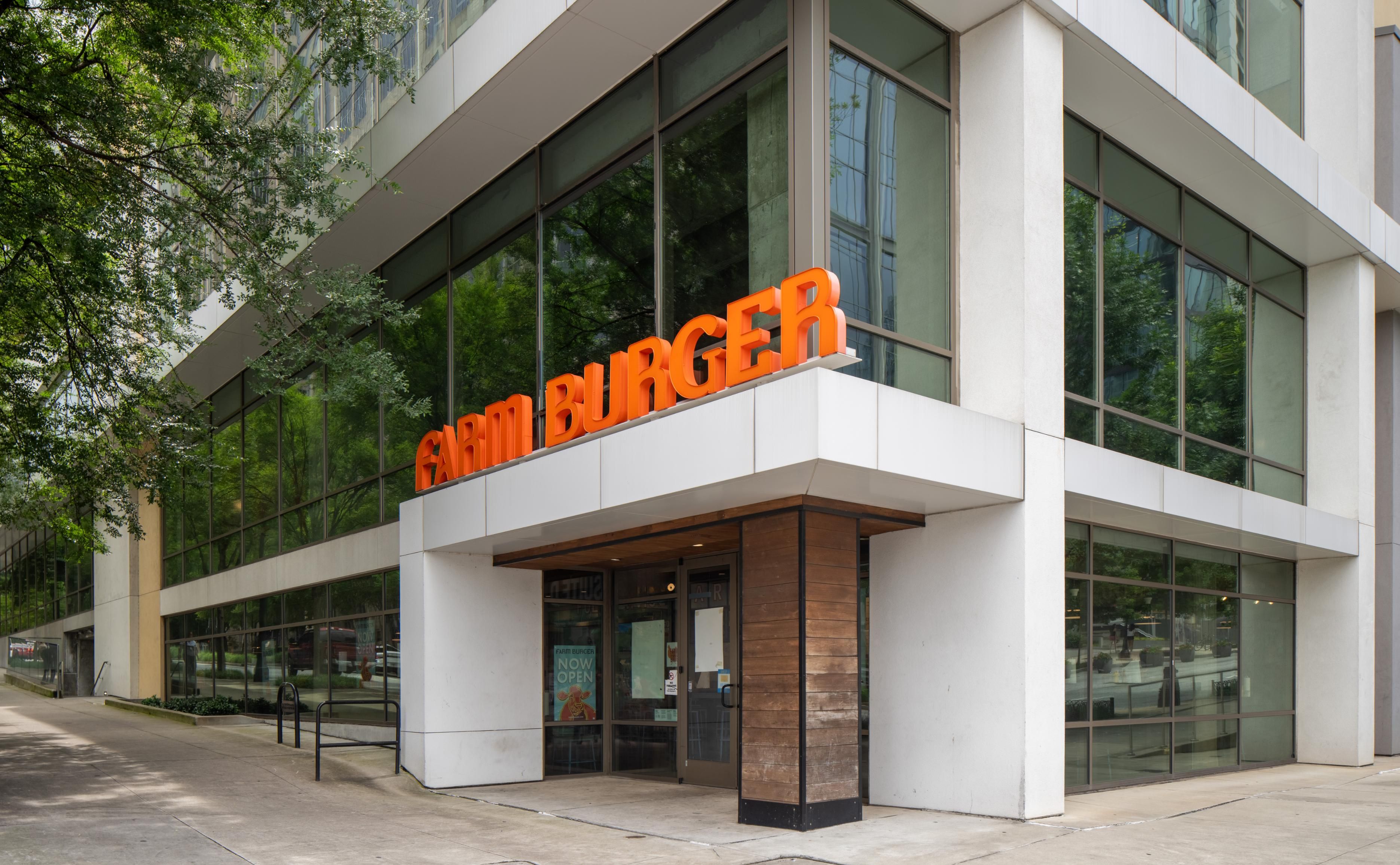 Exterior of a modern building featuring a bright orange "Sushi Burger" sign.