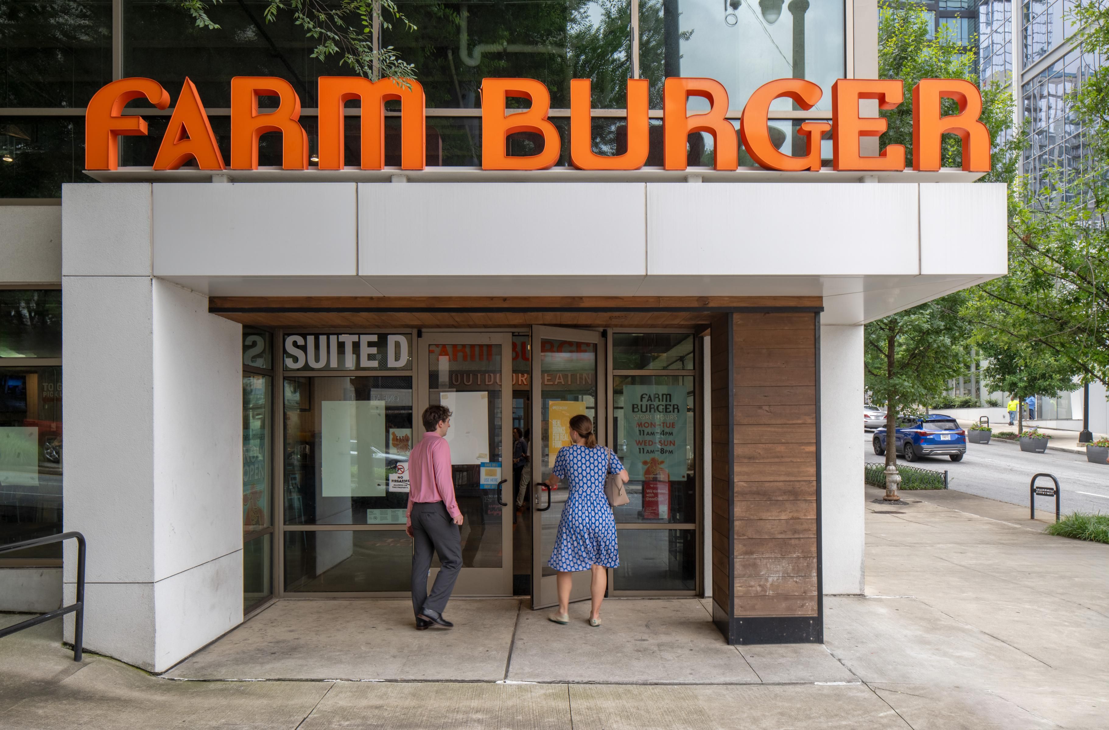 People entering a restaurant with a sign that says "FARM BURGER."