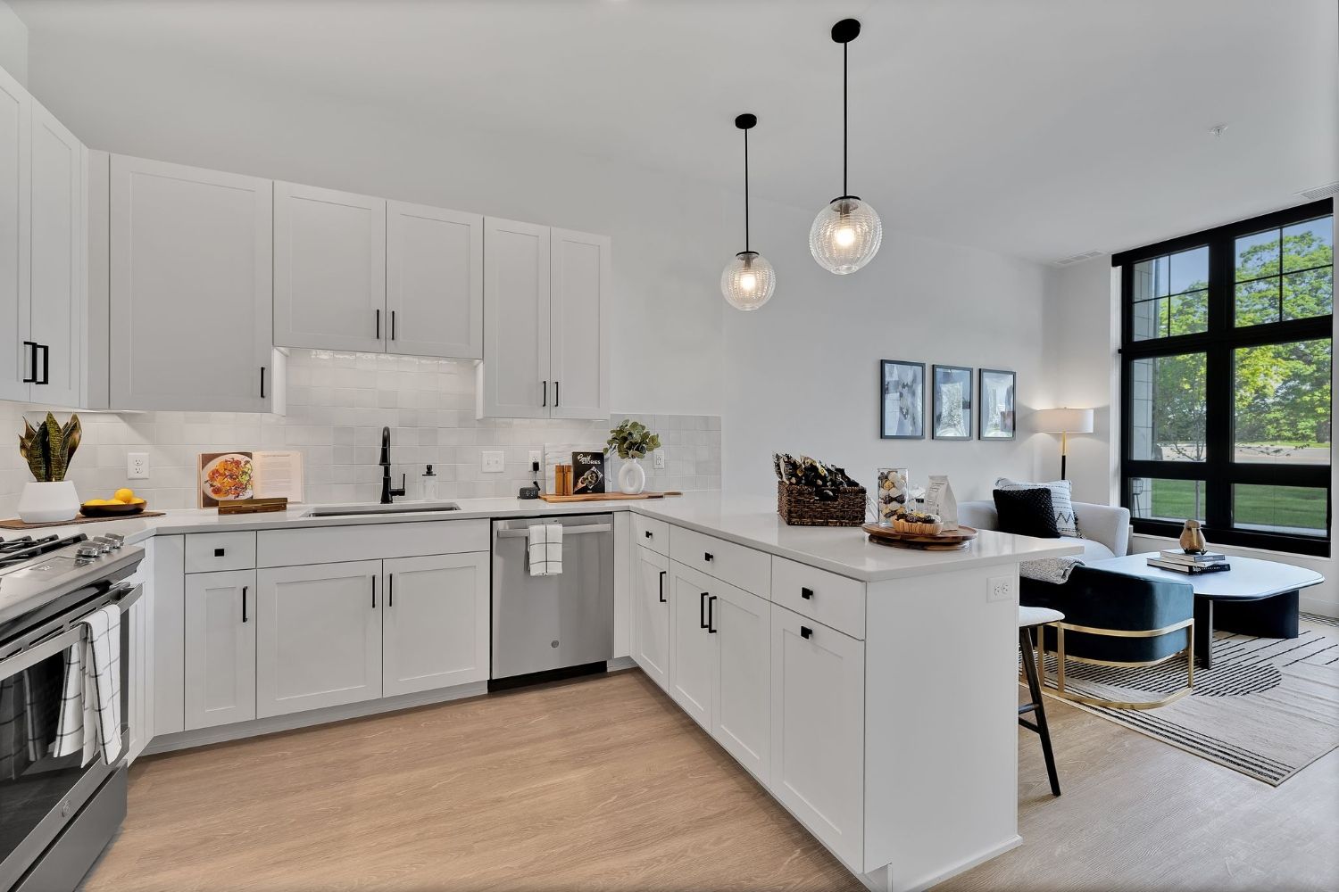 Modern kitchen with white cabinetry, stainless steel appliances, and a cozy dining area nearby.