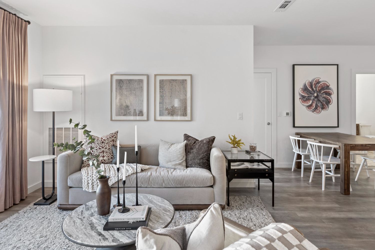 Modern living room with a sofa, coffee table, and dining area featuring minimalist decor.