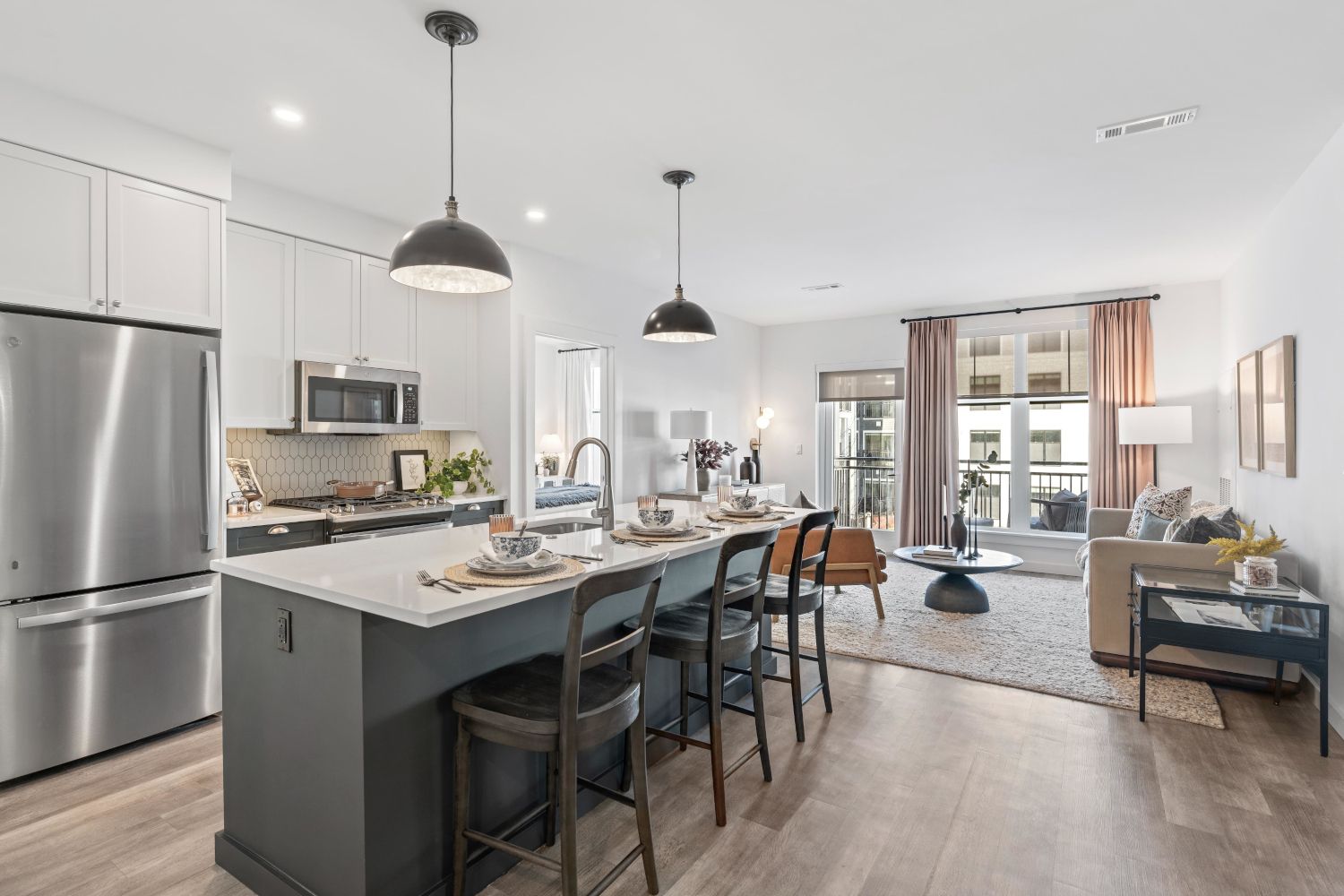 Modern kitchen with a large island, dining area, and living space featuring natural light.