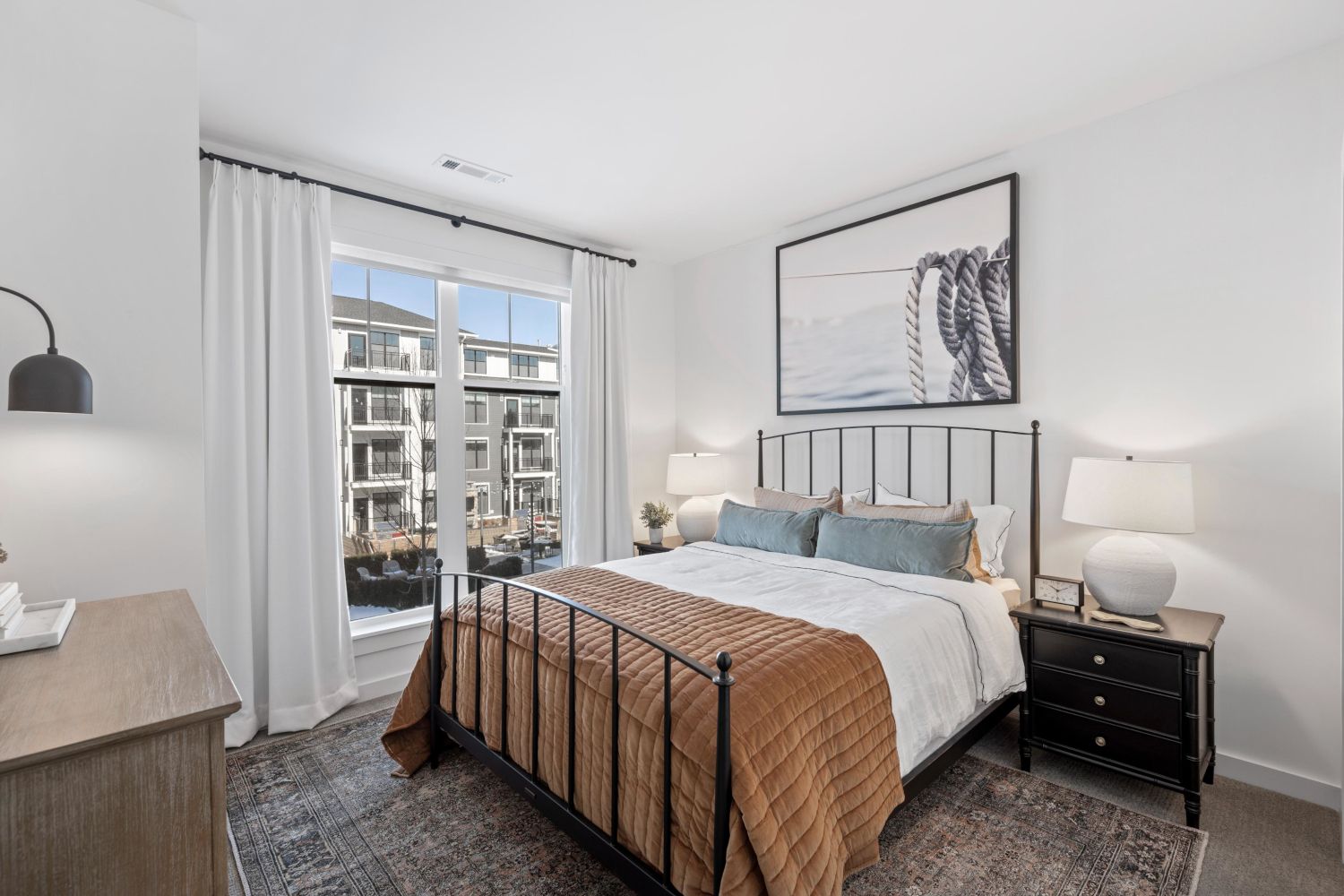 Cozy bedroom featuring a bed, nightstands, and large windows with natural light.