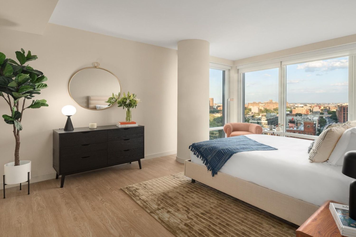 Modern bedroom with large window, stylish furniture, and city view.