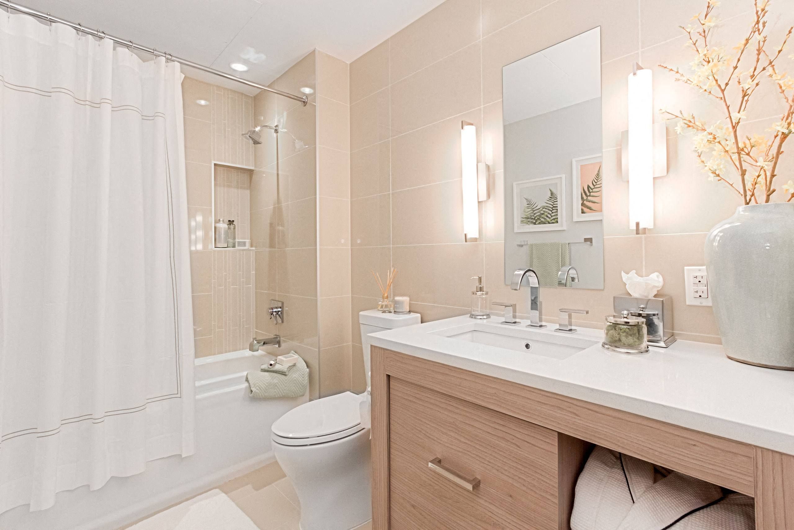 Modern bathroom with bathtub, shower curtain, vanity, and decorative vase.