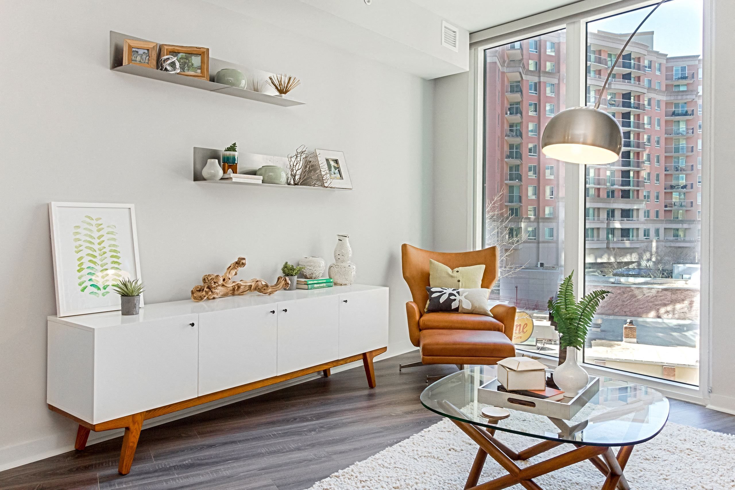 Modern living room with a white cabinet, brown armchair, and large windows.