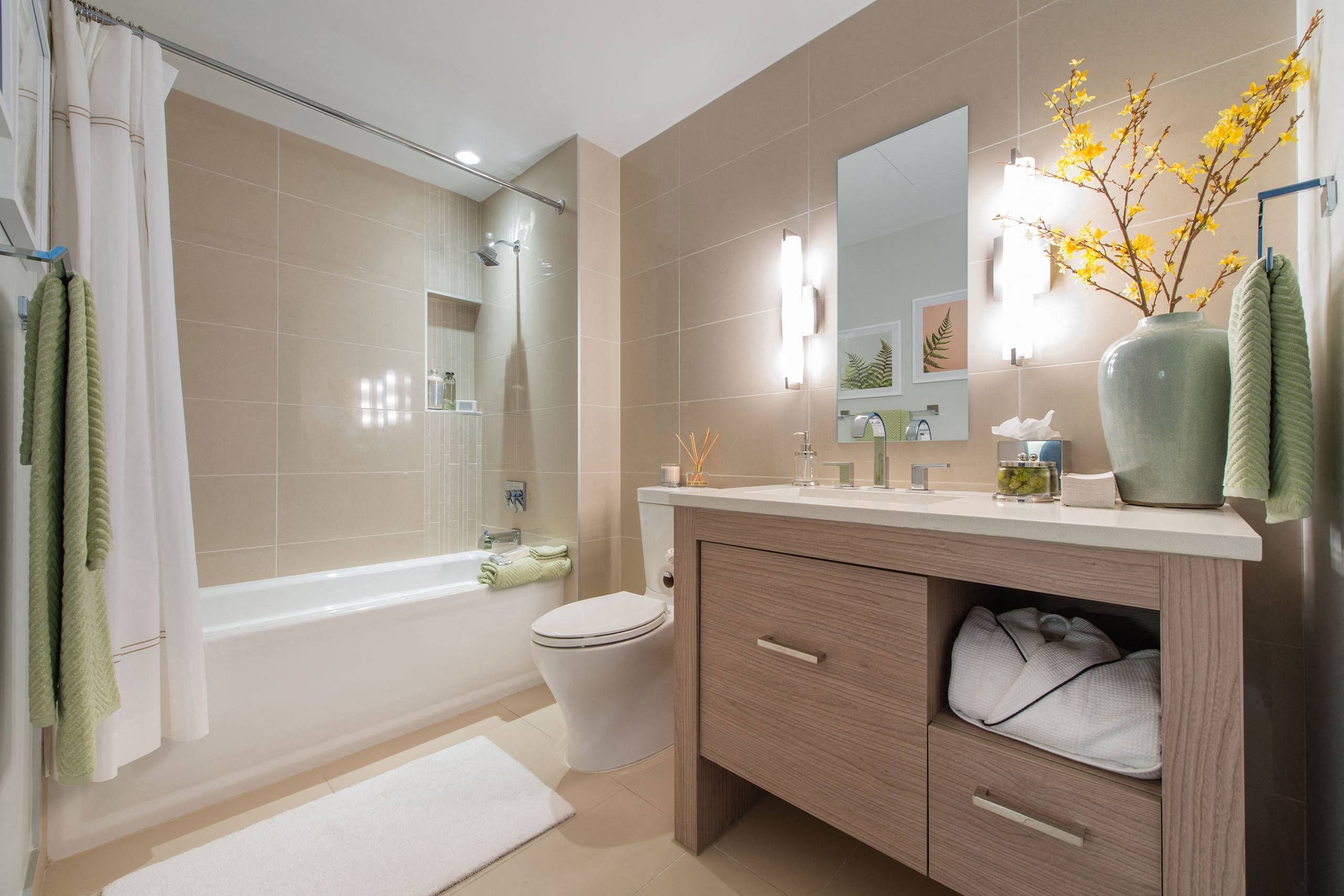 Modern bathroom featuring a tub, vanity, mirror, and decorative plants.