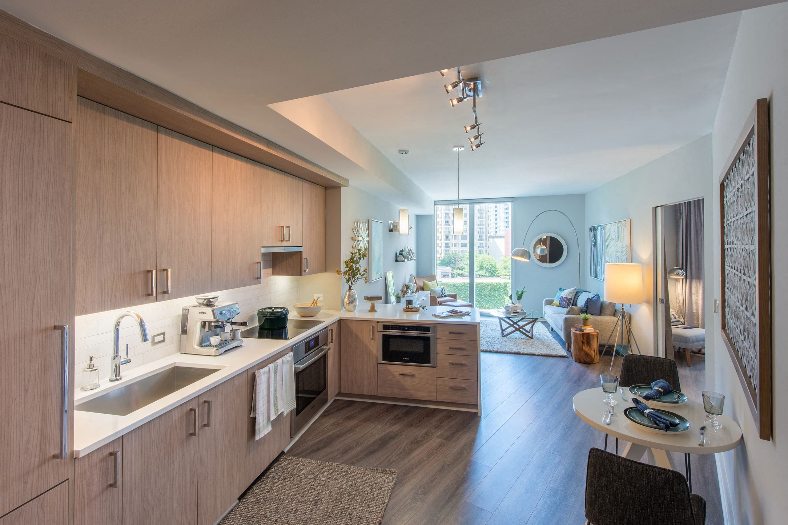 Modern kitchen with wooden cabinets, stainless appliances, and an open living room.