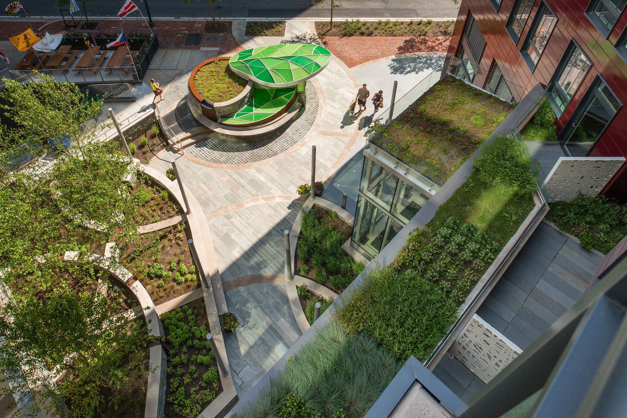 Urban garden with green seating and pathways, viewed from above.