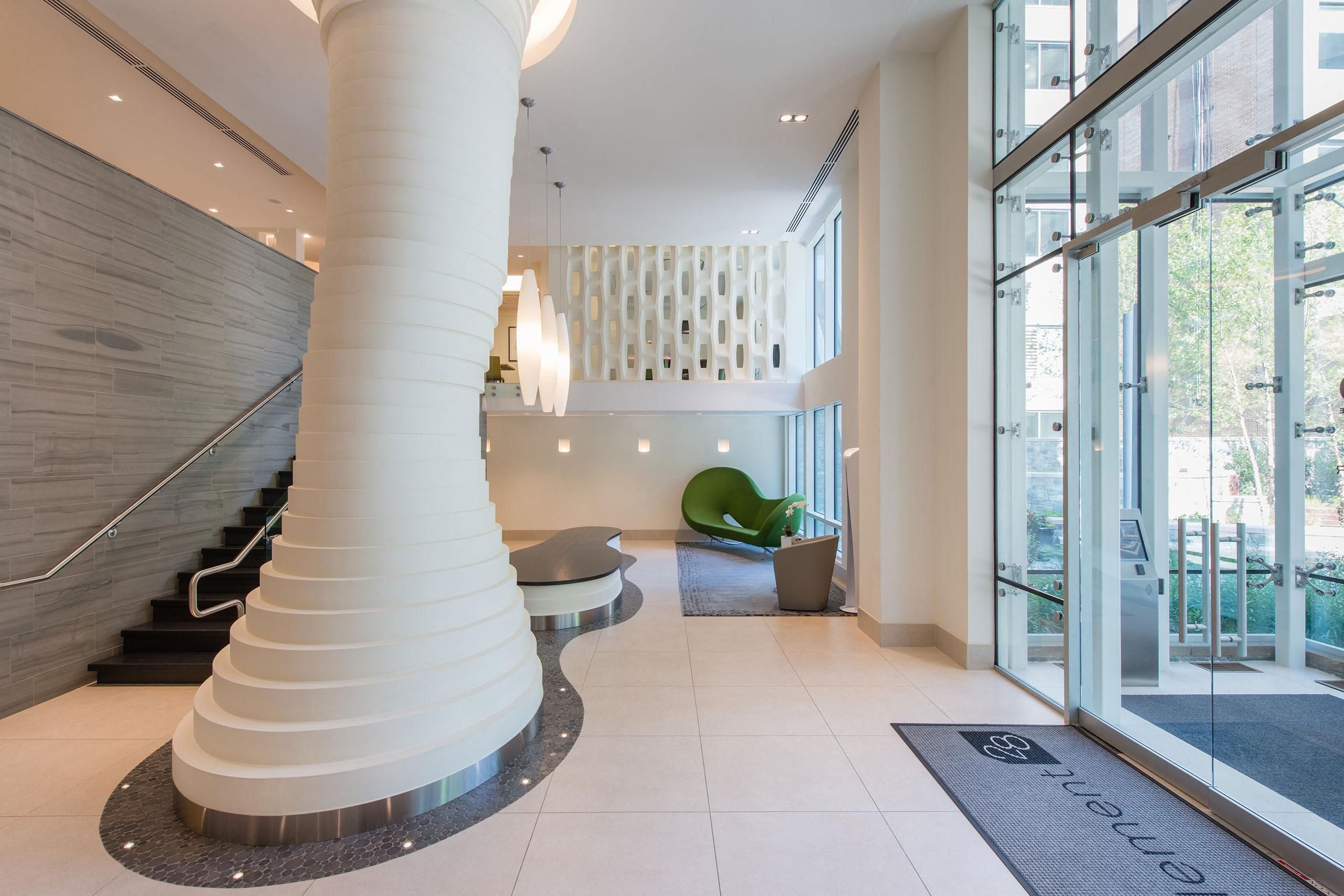 Modern lobby with a spiral column, glass doors, and minimalist furnishings.