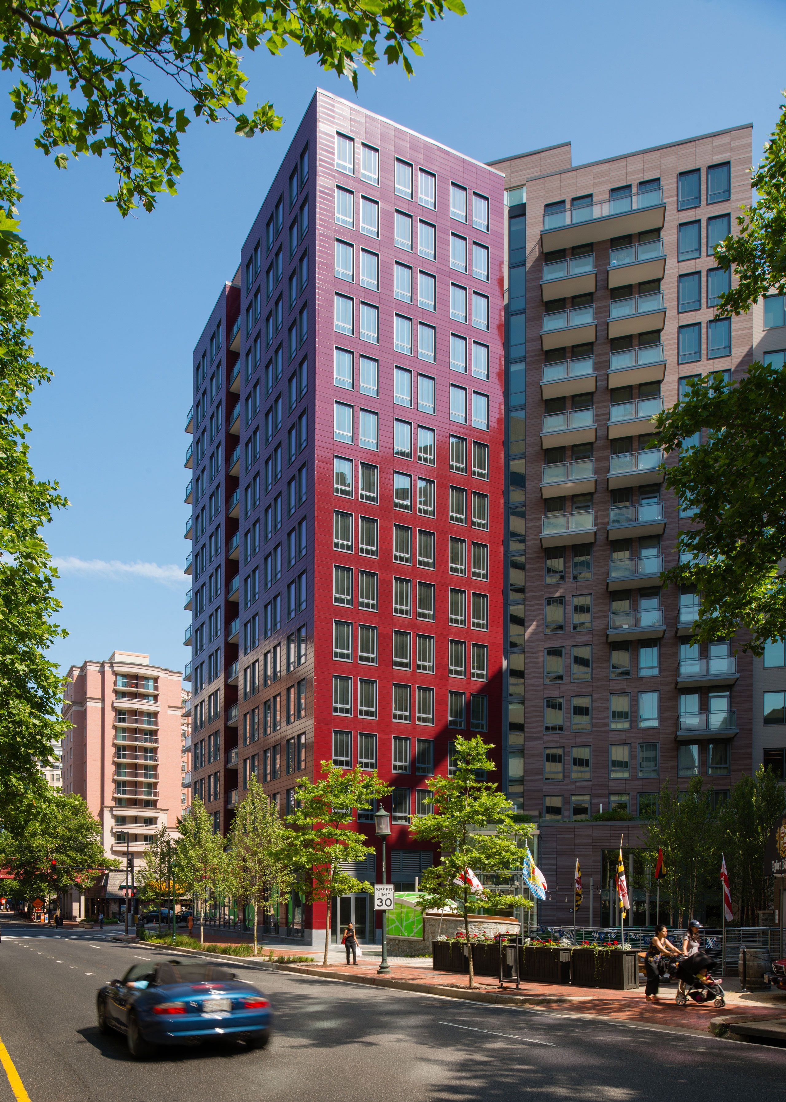 Modern multi-story buildings lined with trees under a clear blue sky.