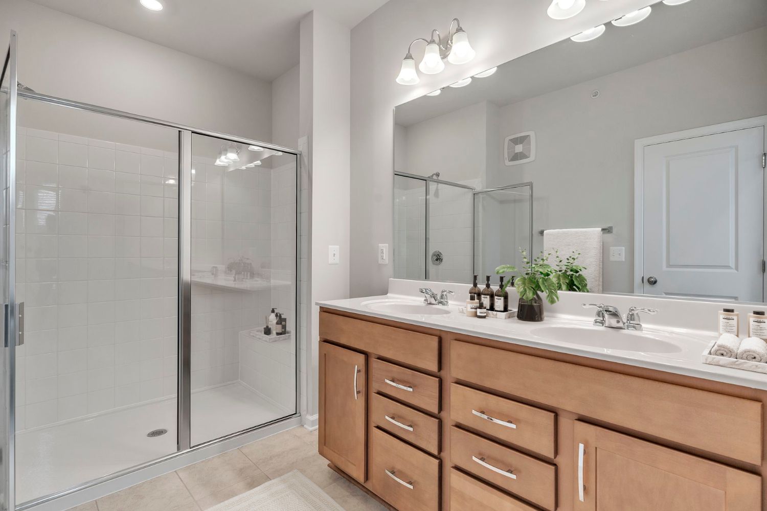 Modern bathroom featuring a vanity with double sinks and a glass shower enclosure.