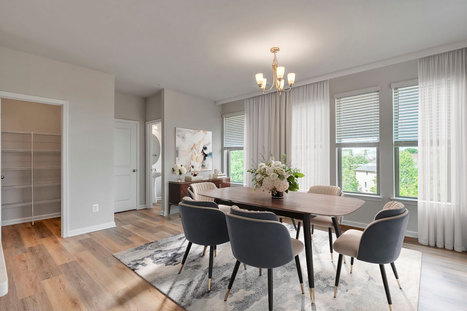 Bright dining room with a wooden table, elegant chairs, and large windows.