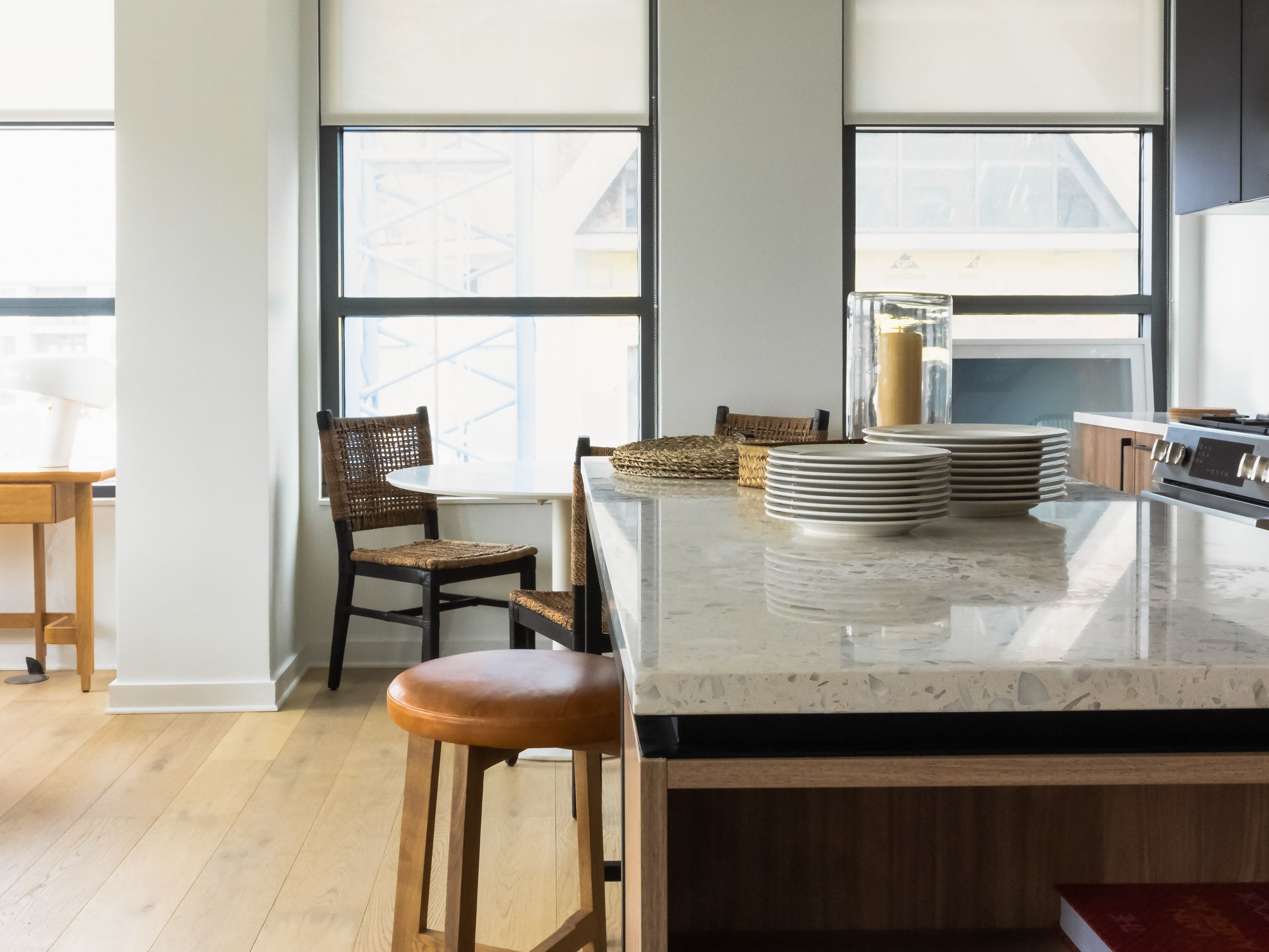 Modern kitchen with a granite island, wooden chairs, and large windows.