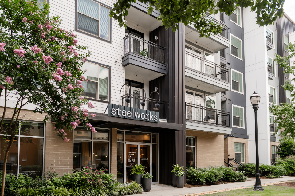 Modern apartment building with balconies and flowering trees.