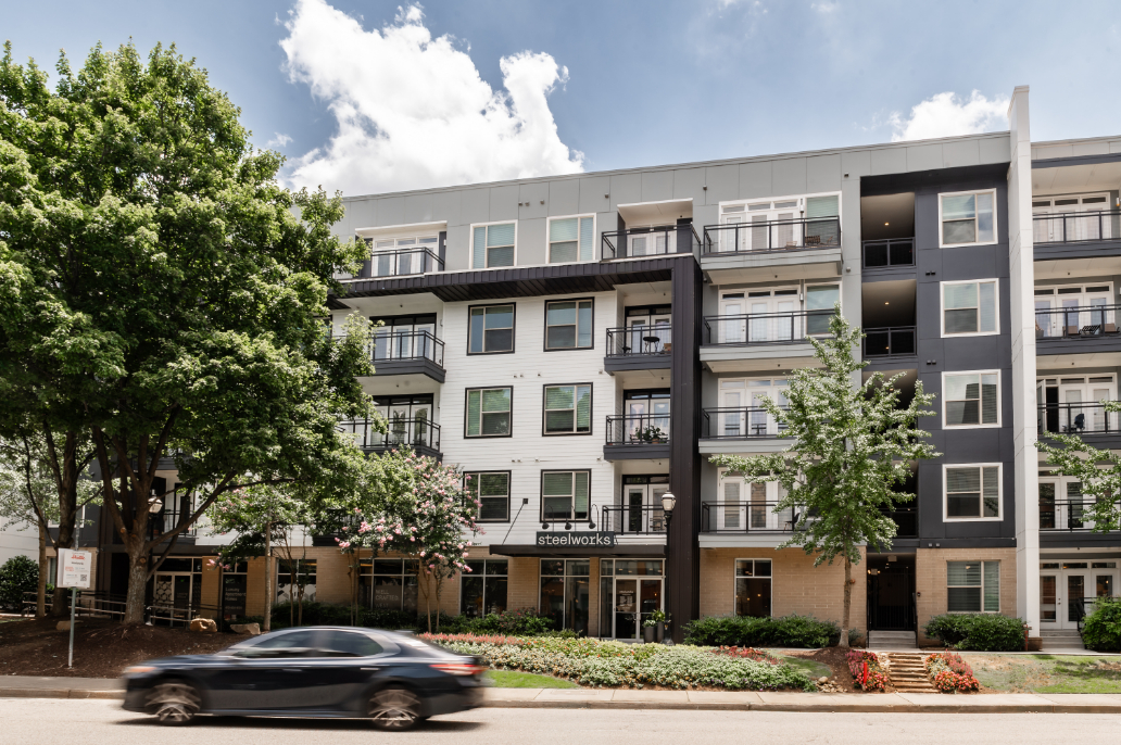Modern apartment building with multiple floors and trees in front.