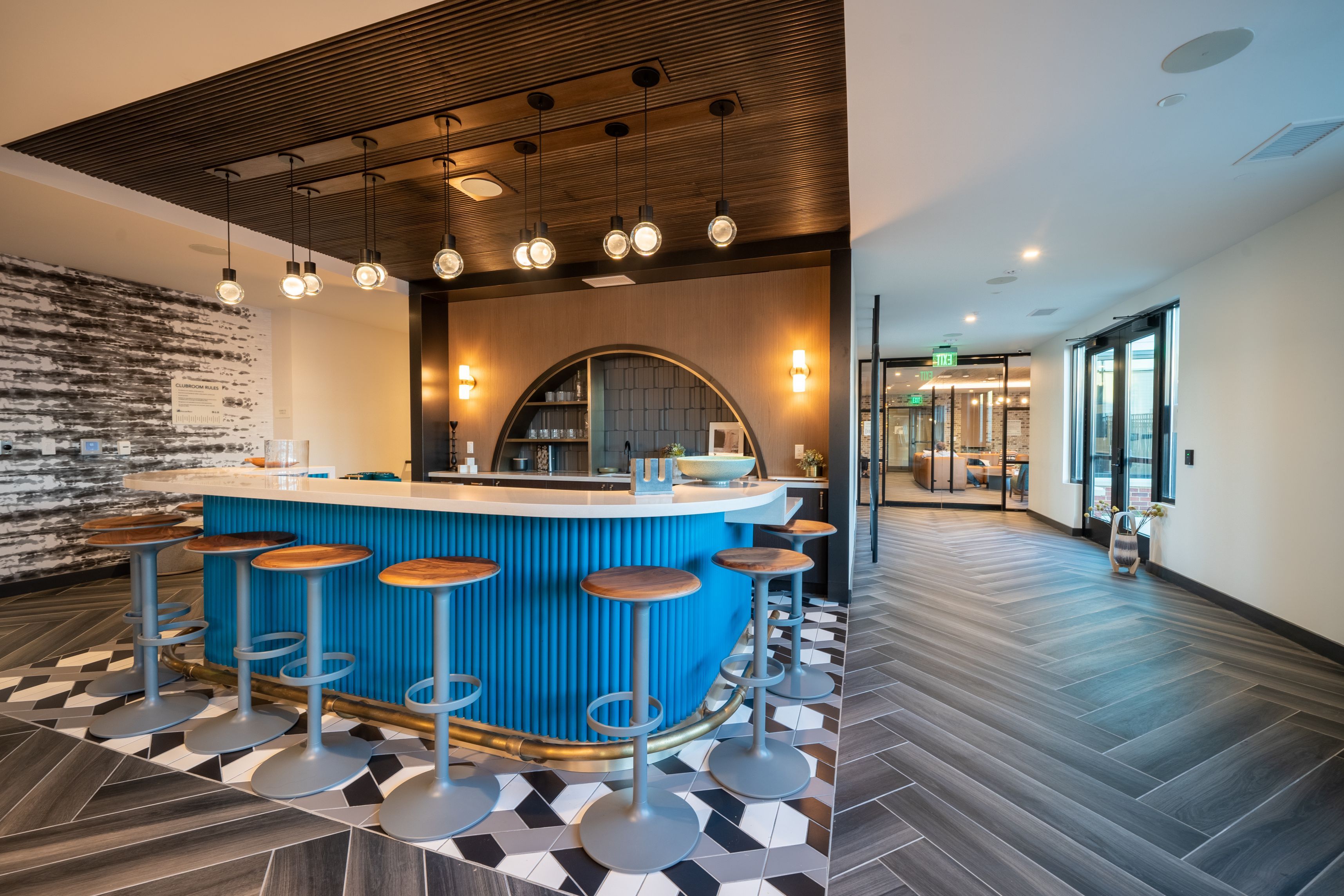 Modern bar area with a blue counter, wooden accents, and geometric tile flooring.