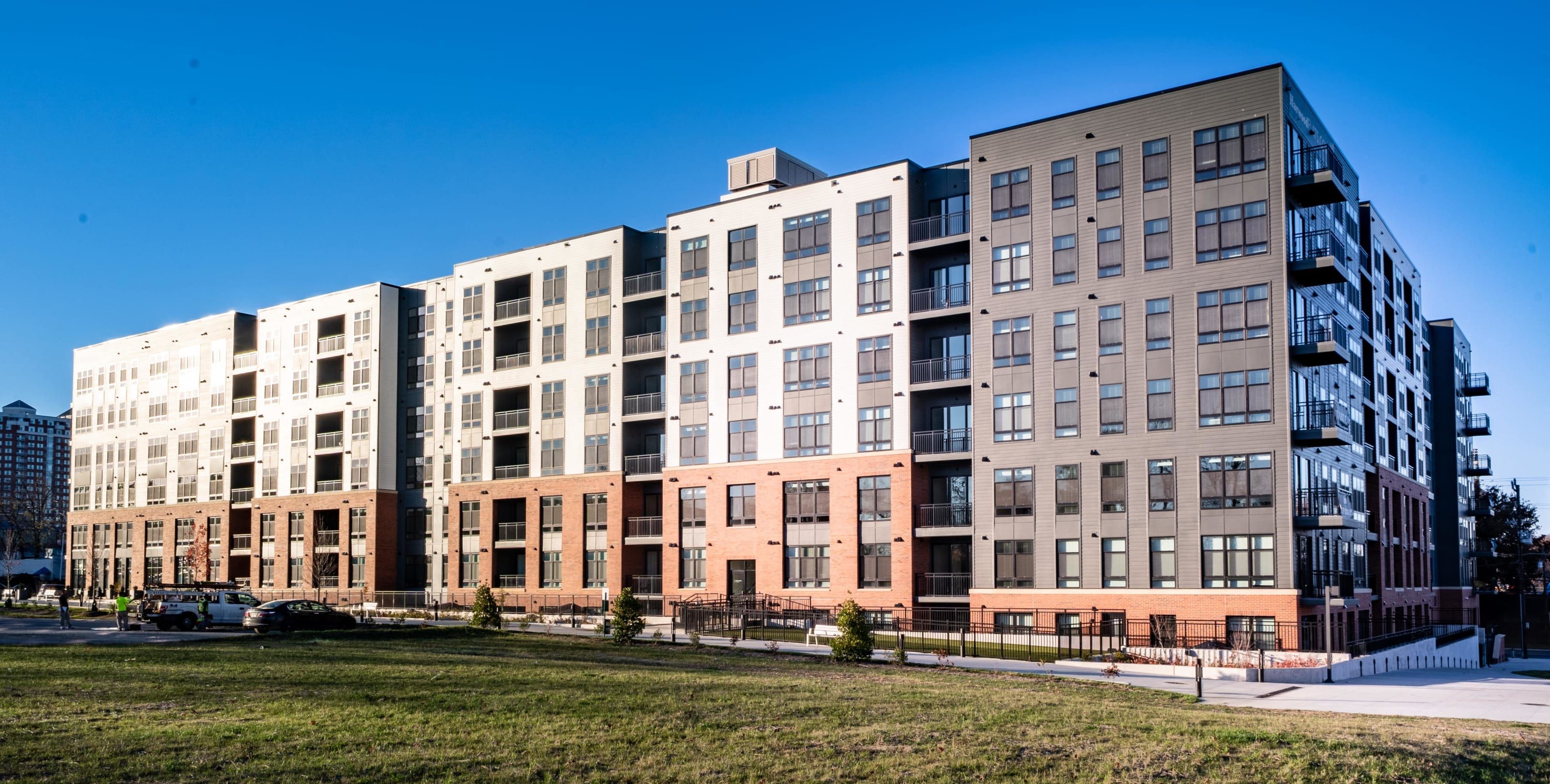 Modern apartment building with multiple floors and balconies against a blue sky.