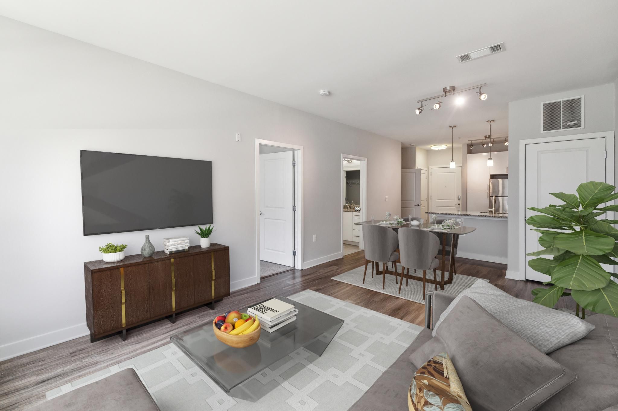 Modern living room with a sofa, coffee table, and dining area in a light, airy space.