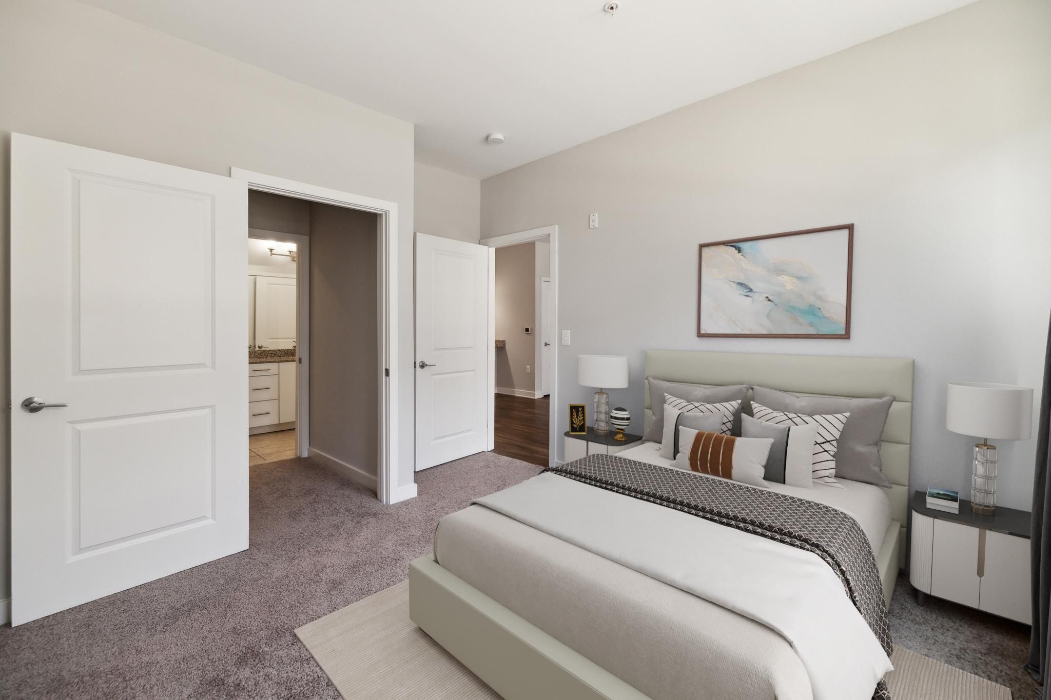 Modern bedroom with a neutral color palette and ensuite bathroom entrance.