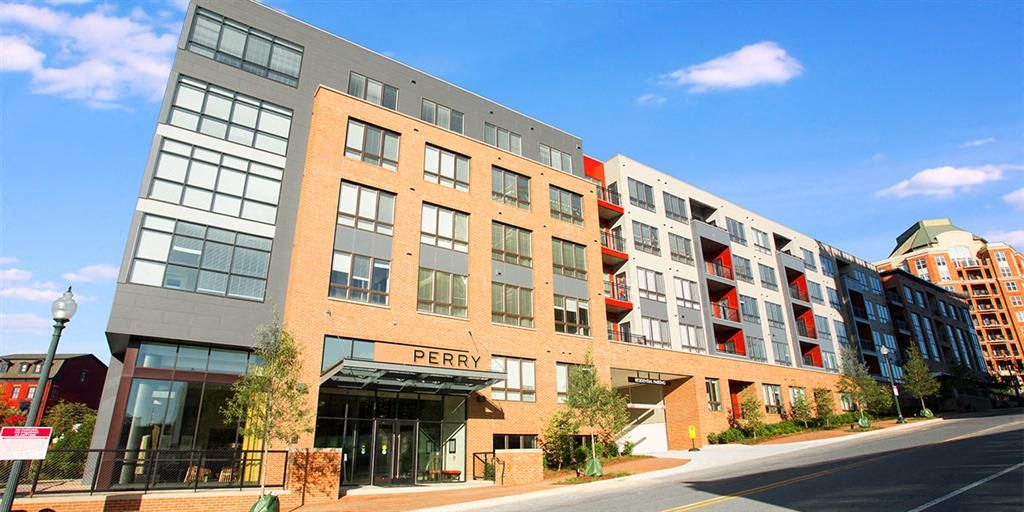 Modern apartment building with large windows and balconies against a clear blue sky.