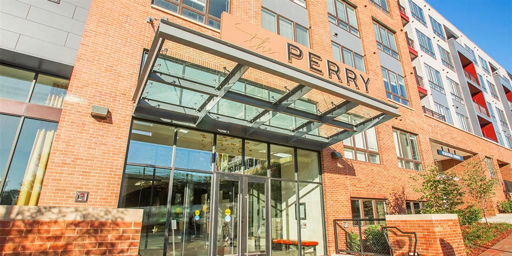 Entrance of a modern brick apartment building with "PERRY" sign.