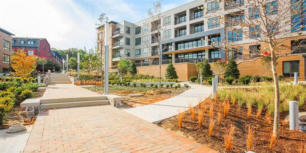 Modern residential complex with landscaped pathways and trees.