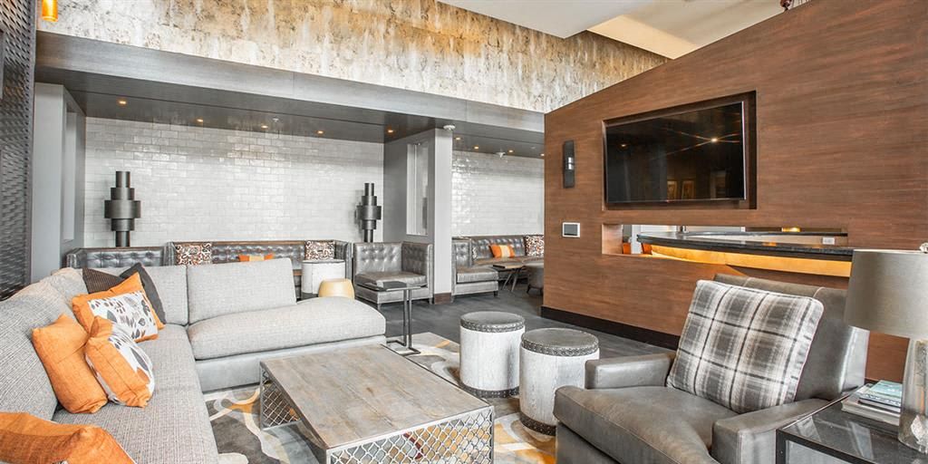 Modern lounge area with a gray sofa, decorative pillows, and a wall-mounted TV.