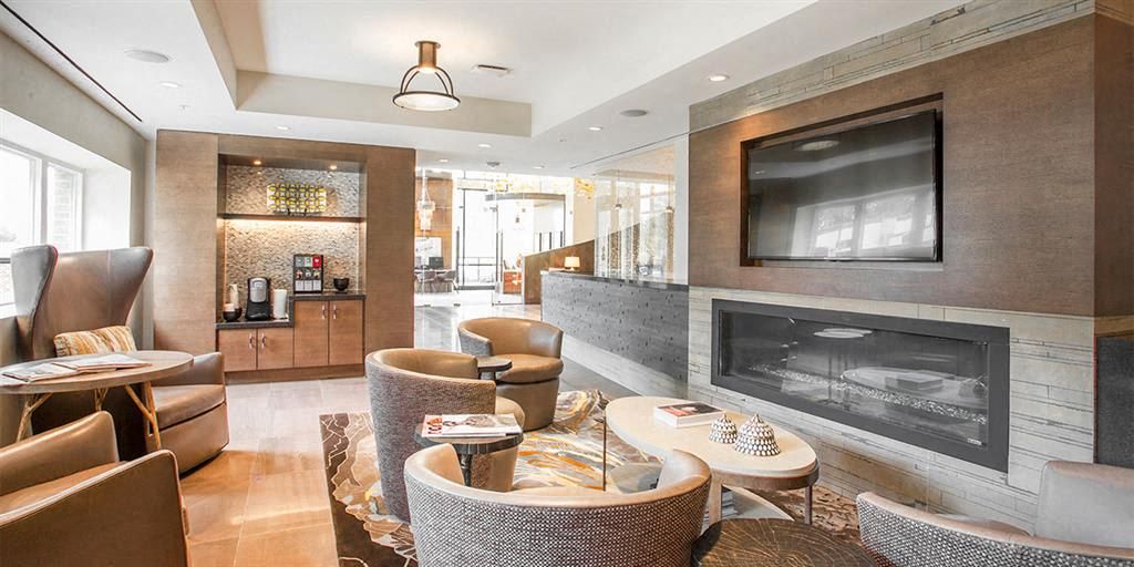 Modern lounge area with couches, a fireplace, and a wall-mounted TV.