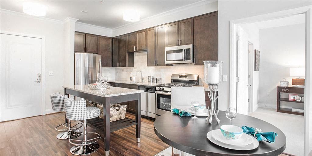 Modern kitchen with dark cabinets, stainless appliances, and a dining table set for two.